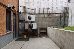 Photo of an urban industrial setting with brick walls and air conditioning units outdoors.